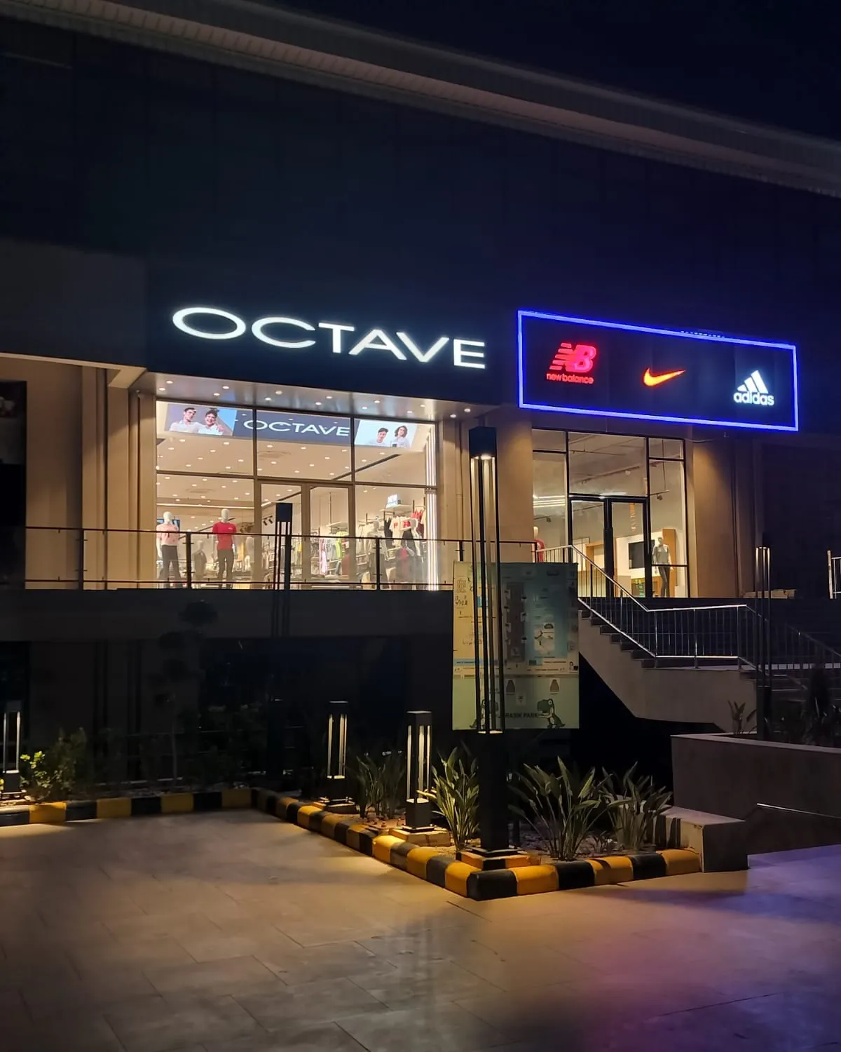 OCTAVE storefront at night, illuminated fascia signage above a glazed double-height frontage.